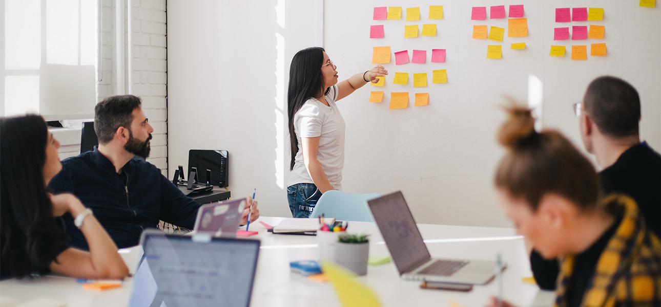 A woman in a conference room arranges sticky notes on the wall