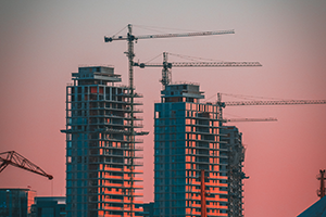 Cranes build three skyscrapers at sunset